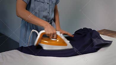 Unrecognizable woman ironing a man's shirt at home. Domestic life chore.