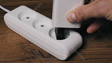 Plugging White Charger into Outlet Power Strip