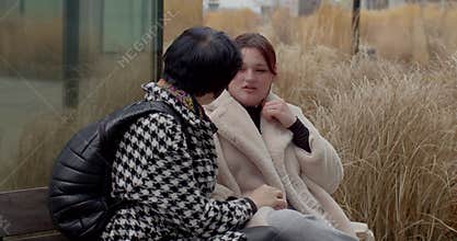 Caucasian females exchanging gentle words amid lush park surroundings