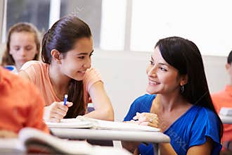 Teacher Helping Female High School Student In Classroom