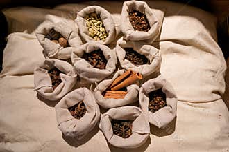 Assorted spices displayed in fabric bags on a neutral background