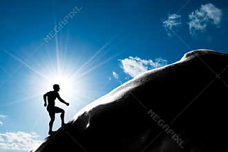 Silhouette of a man running up hill to the peak of the mountain