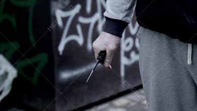A robber or bandit on the street opens a knife and threatens to use a standard or robbery