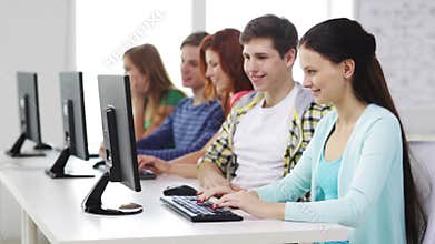 Smiling students working with computers at school