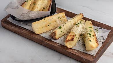 Close-up of golden, seasoned cassava fries on a wooden serving board with parsley and cheese