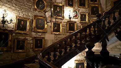 Grand staircase corridor lined with hundreds of antique portraits in ornate gold frames