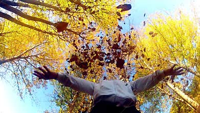 Woman throws fall leaves into air