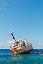 Rusty the Edro III shipwreck, Pegeia, Cyprus leaning on its side in calm blue sea under clear sky