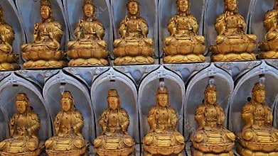 Rows of identical golden Buddha statues in arched niches at Kek Lok Si Temple, Penang. Multiple Guanyin deity sculptures arranged