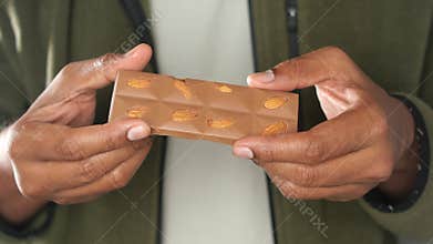 Holding a chocolate bar with almonds in hands