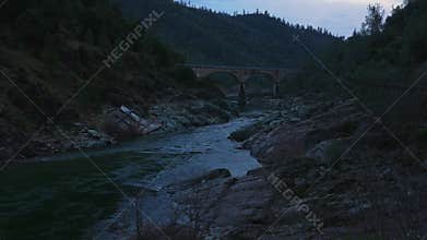 Twilight River with Arched Bridge in Rocky Canyon