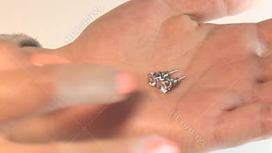Woman looking at the earrings at her hands in the jewelry shop, hand with diamond, hand holding a diamond