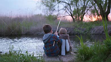 Family weekend, fishermen little brothers sit on pier and fish with a wooden fishing rod, back view