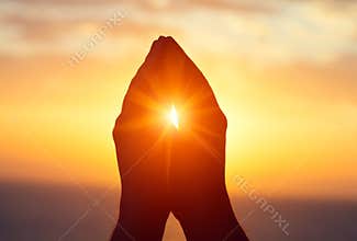 Silhouette of male  raising hands praying for God`s blessings at sunset or sunrise light