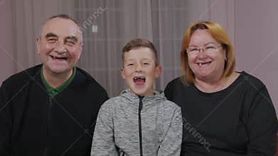 Happy toothless grandfather, granny and grandson together are laughing in front of the camera. Closeup.
