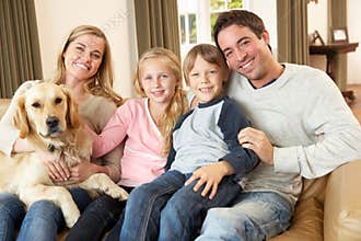 Happy young family sitting on sofa holding a dog
