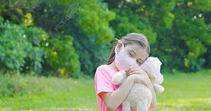 Stress little girl holding toy bear in medical protective mask