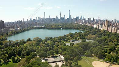 AERIAL: Beautiful Central Park view with lake and Manhattan Skyline in Background at sunny summer day, New York City