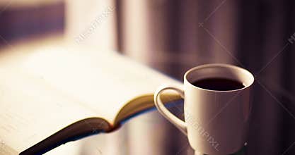 Closeup cup of coffee with book indoors