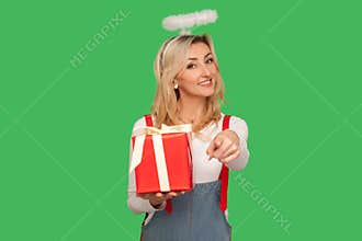 Happy birthday to you! Portrait of beautiful angelic adult woman with halo holding gift box and pointing to camera