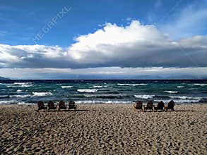 Empty Adirondack chairs along the shoreline of Lake Tahoe from the Nevada side on a windy fall day, choppy water