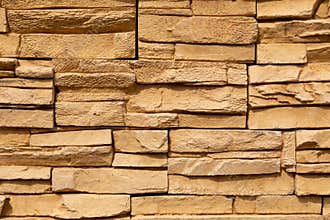 Texture of the yellow surface of a slate stone. Blocks of natural finishing stone for wall decoration. Rough stone background