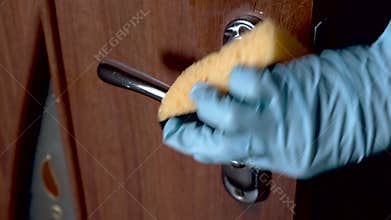 Coronavirus covid-19 prevention cleaning woman wiping doorknob with antibacterial disinfecting wipe.
