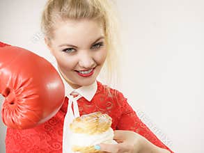 Woman fighting off bad food, boxing cream puff cake