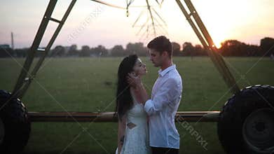Couple in love embraces and kisses under the agricultural sprayer