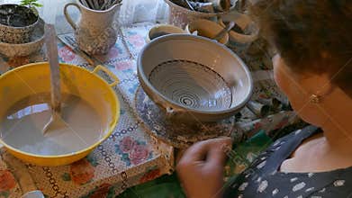 Traditional woman artist in folk art decorates a clay pot