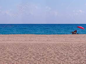 Senior man resting alone on a beautiful white-sand beach somewhere in Spain, turquoise sea on a summer sun
