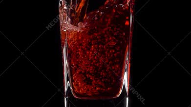Trendy Nature Drink. Super slow motion shot of pouring pomegranate juice into a transparent glass against black