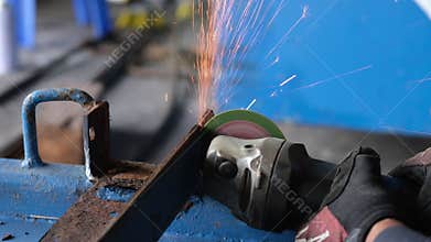 The worker is using a steel grinder to cut the iron and make a spark in workshop.