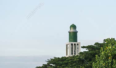 Lighthouse tower among green leaves on the beach
