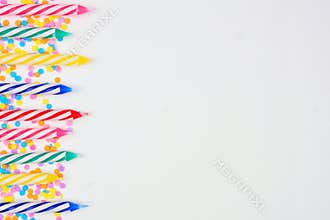 Birthday cake candles with candy sprinkles. Side border on a white background.