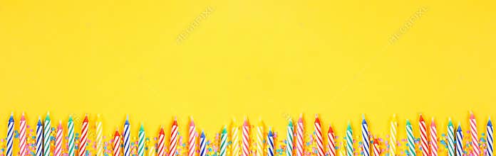 Birthday cake candles with candy sprinkles. Banner with bottom border on a yellow background.