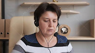 Woman wear headset communicating by conference call speak looking at computer at home office, video chat job interview