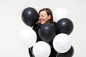 Young woman girl posing celebrating holding black and white air balloons isolated on white wall background studio