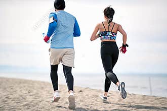 Fitness man and woman  running along beach