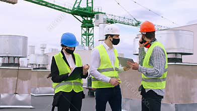 COVID-19 construction site group of specialists engineers architect analyzing the plan of construction discussing some