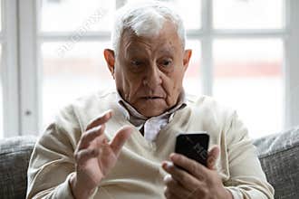 Shocked 70s retired old man looking at smartphone screen.