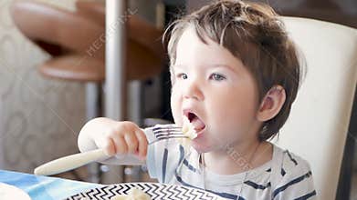 The child at the table eating hot food. Not cooled Breakfast child