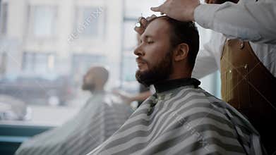 Bearded Client Sits on the Chair During the Hair Cut.
