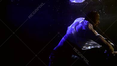 Black man is floating inside water of swimming pool, underwater shot, dream and magic