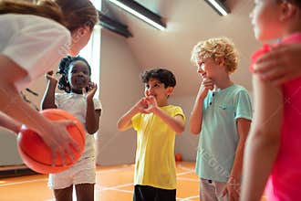 Children smiling to their sports teacher in the gym.