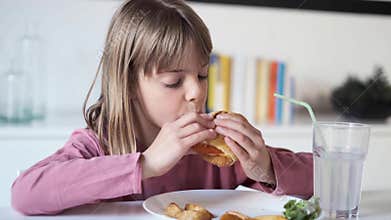 Pretty little girl eating a complete hamburger at home