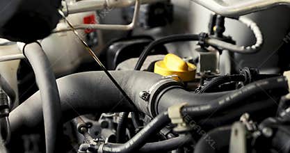Mechanic in garage doing car engine oil change and level inspection