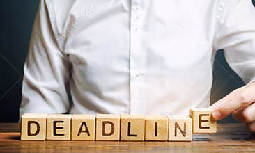 Businessman puts wooden block with the word Deadline. A narrow field of time by which an objective must be accomplished. Time