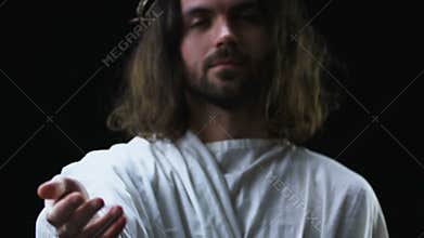 Kind Jesus Christ stretching helping hand against dark background, christianity