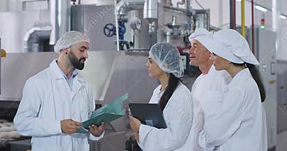 Bakery industry man engineer his assistance and baker chef and young baker lady have a meeting , man engineer explaining